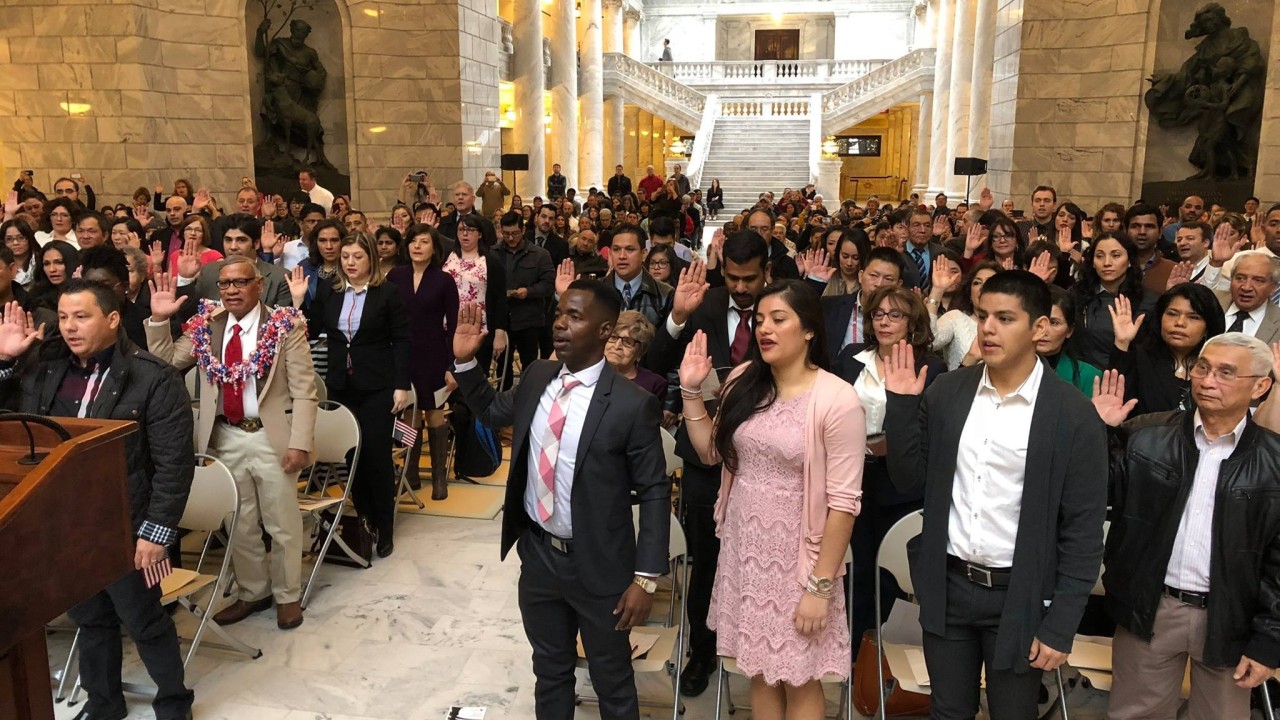 New Americans raising their right hands during a naturalization ceremony at the Utah State Capitol